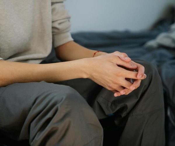 Mani intrecciate di una persona seduta in atteggiamento riflessivo
